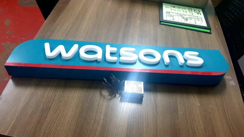 Acrylic Watsons signage with raised white letters on table and electronic device, Quezon City install by M&G Global Ads.