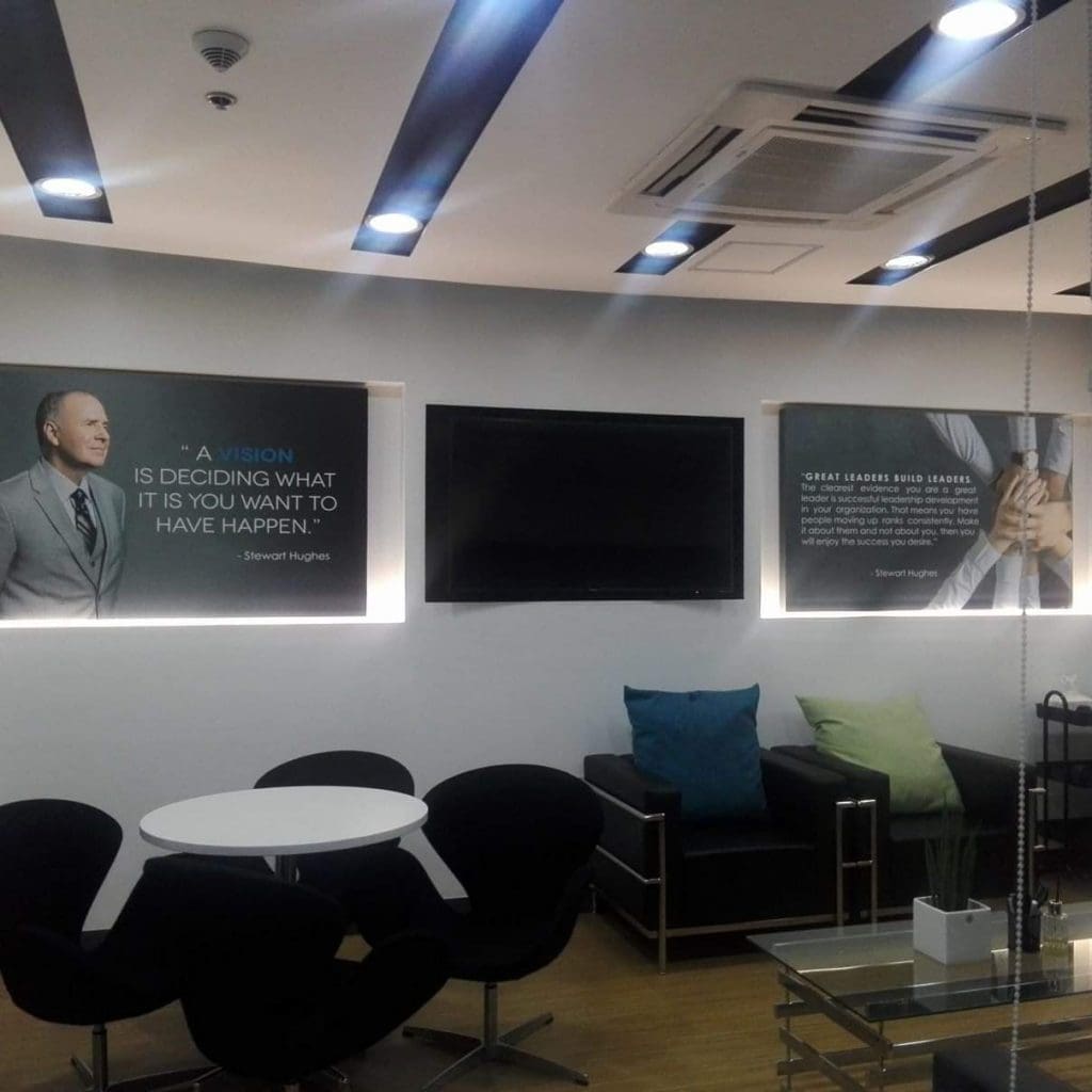 Office lounge with indoor signage for corporate client, black chairs, posters, and TV in Makati by M&G Global Ads.