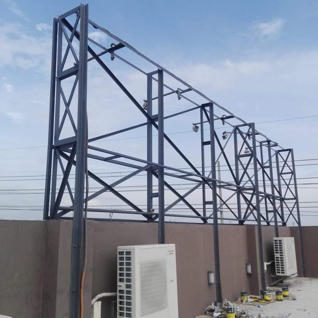 Pylon signage frame on a rooftop with A/C units below in Makati, partly cloudy sky, by M&G Global Ads.