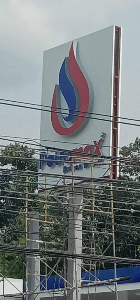 PTT Station outdoor signage metallic sign in Quezon City, partly obscured by wires and scaffolding, by M&G Global Ads.