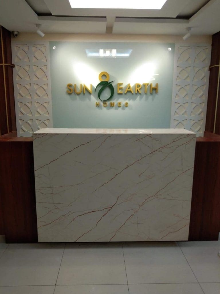 Acrylic gold metallic SUN EARTH HOMES signage at Makati reception area, marble counter, glass wall by M&G Global Ads.