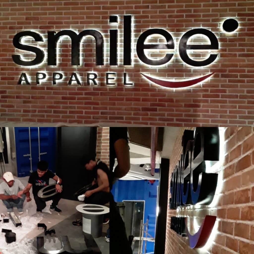 Backlit smilee APPAREL LED acrylic signage installation in Makati, with assembly team. Modern indoor signage by M&G Global Ads.