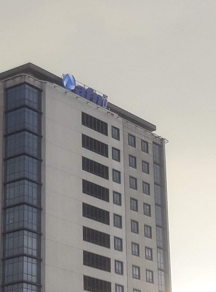 Acrylic building signage for ATTI on a tall modern office in Makati, blue and white logo at top, by M&G Global Ads.