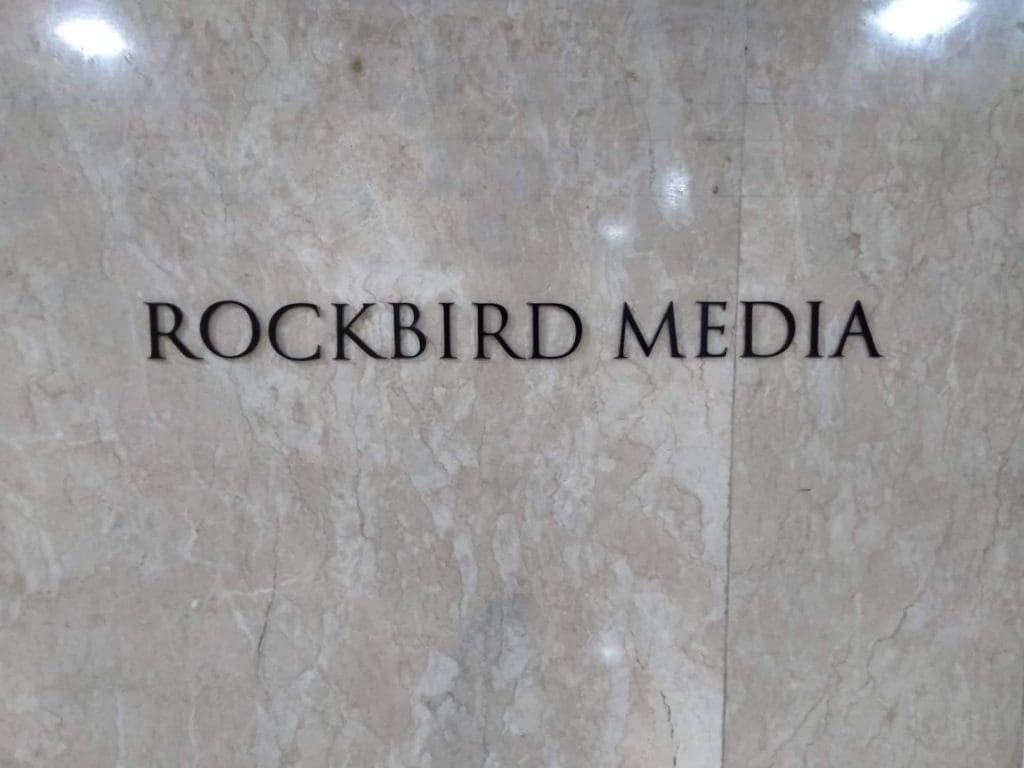 Acrylic signage for ROCKBIRD MEDIA on a polished marble wall in Makati by M&G Global Ads.