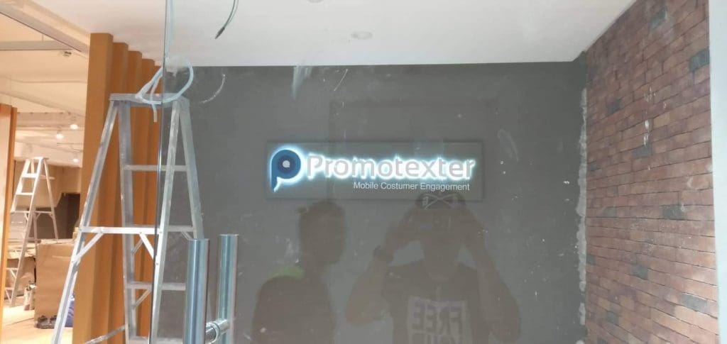 Acrylic office signage for Promotexter in modern Makati workplace under construction with ladders, by M&G Global Ads.