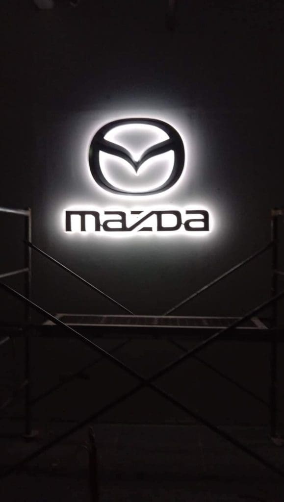 Outdoor LED signage for Mazda, featuring illuminated logo and text with scaffolding, in Quezon City by M&G Global Ads.