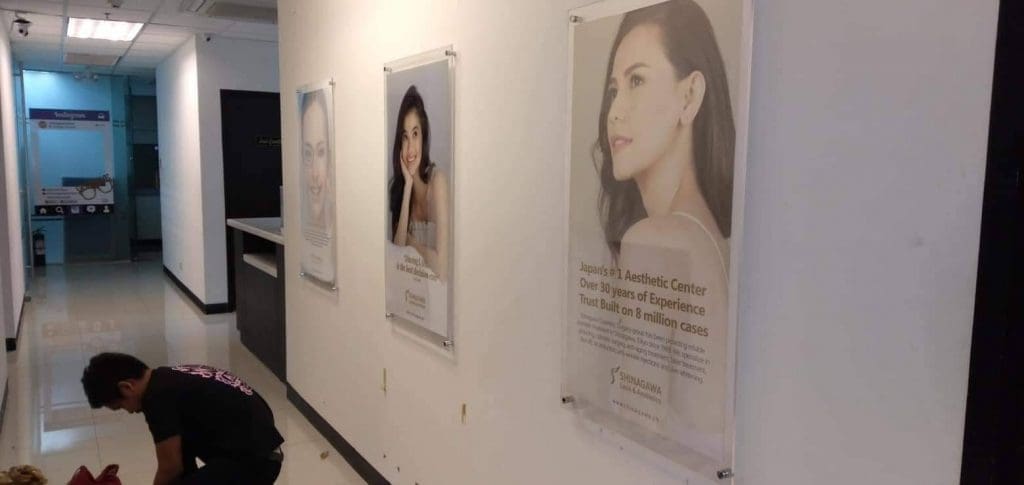 Acrylic signage and wall posters at an aesthetic clinic with patient results, Quezon City location, by M&G Global Ads.