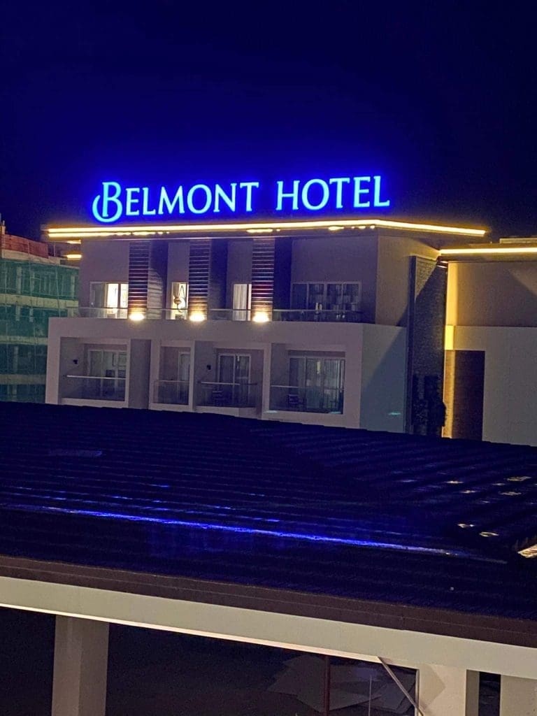 Belmont Hotel bright blue acrylic rooftop signage in Makati, with warmly lit balconies at night by M&G Global Ads.