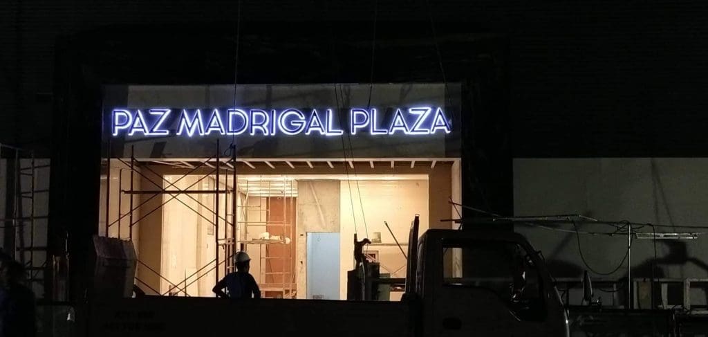 LED signage for PAZ MADRIGAL PLAZA at a Makati construction site with scaffolding and a truck, by M&G Global Ads.