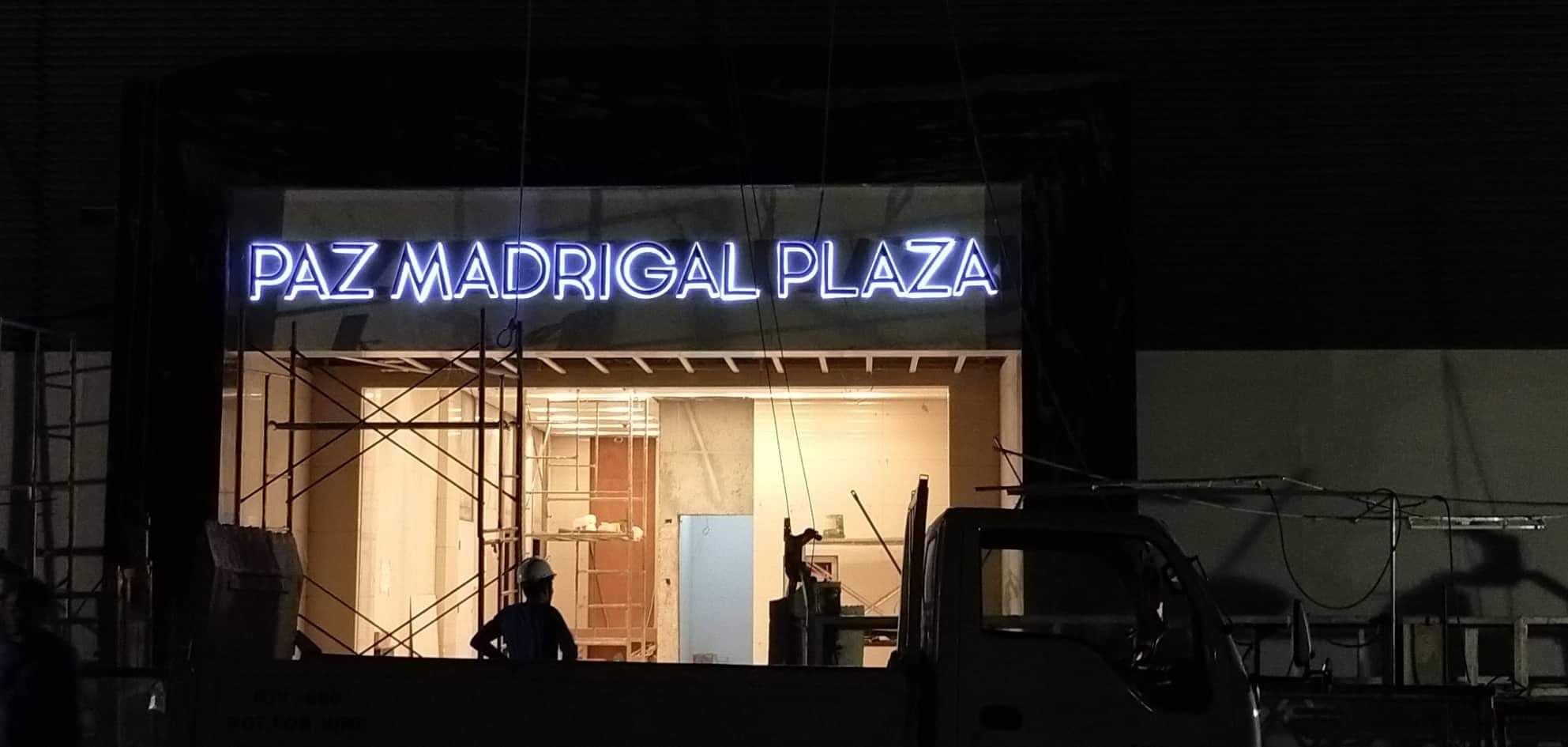 LED signage for PAZ MADRIGAL PLAZA at a Makati construction site with scaffolding and a truck, by M&G Global Ads.