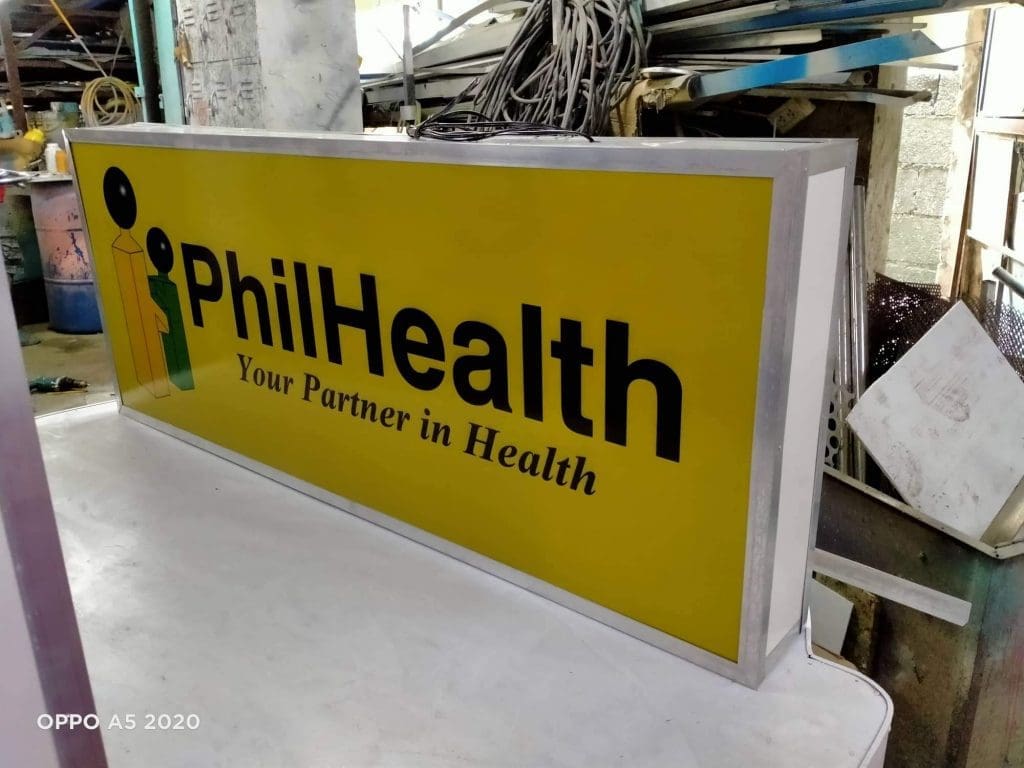 Rectangular PhilHealth building signage in Makati with green/black logo and text, workshop view. By M&G Global Ads.