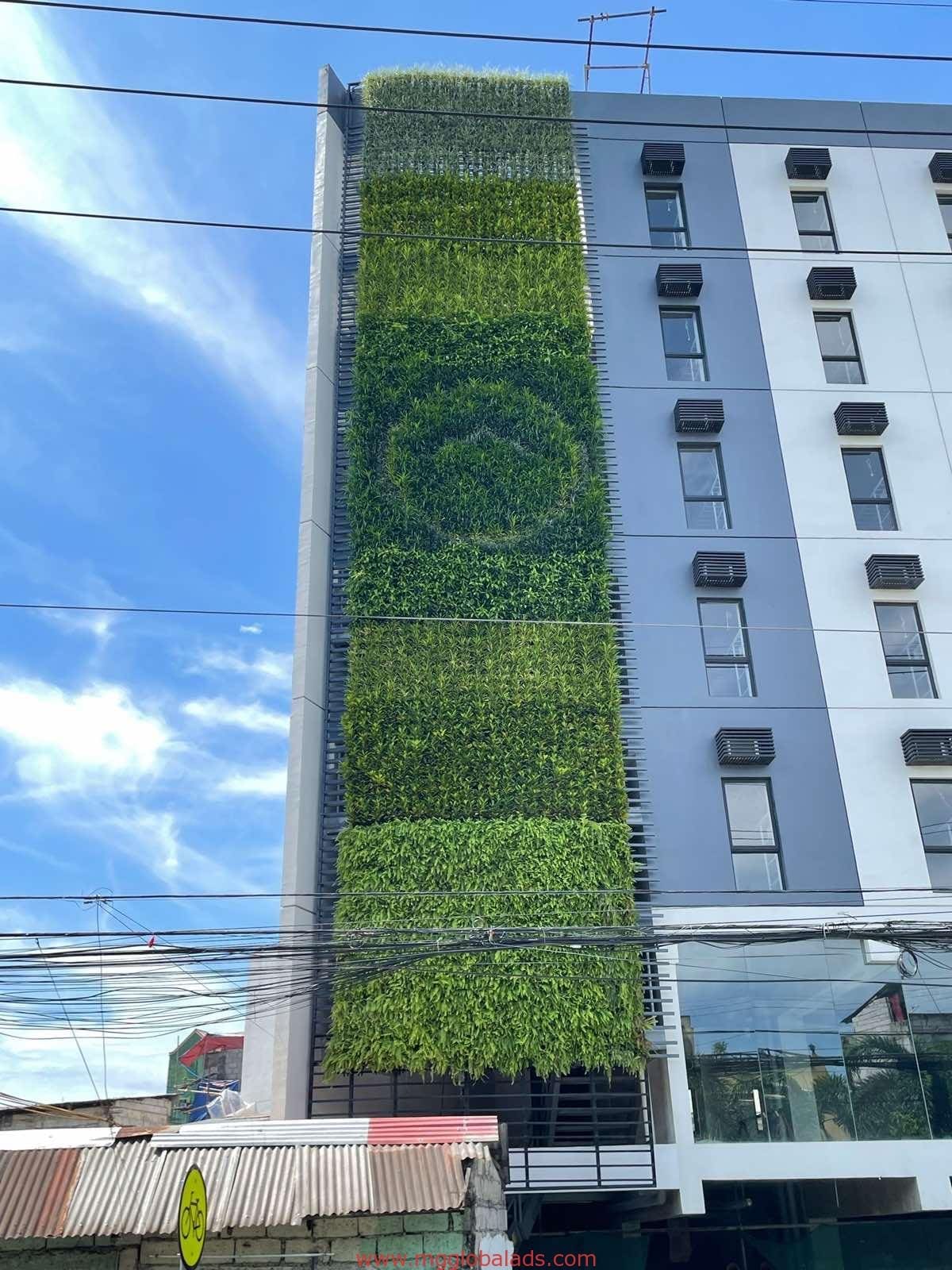 Greenwall and Moss Wall on a modern building with a vertical garden in Makati, windows, and AC units by M&G Global Ads.