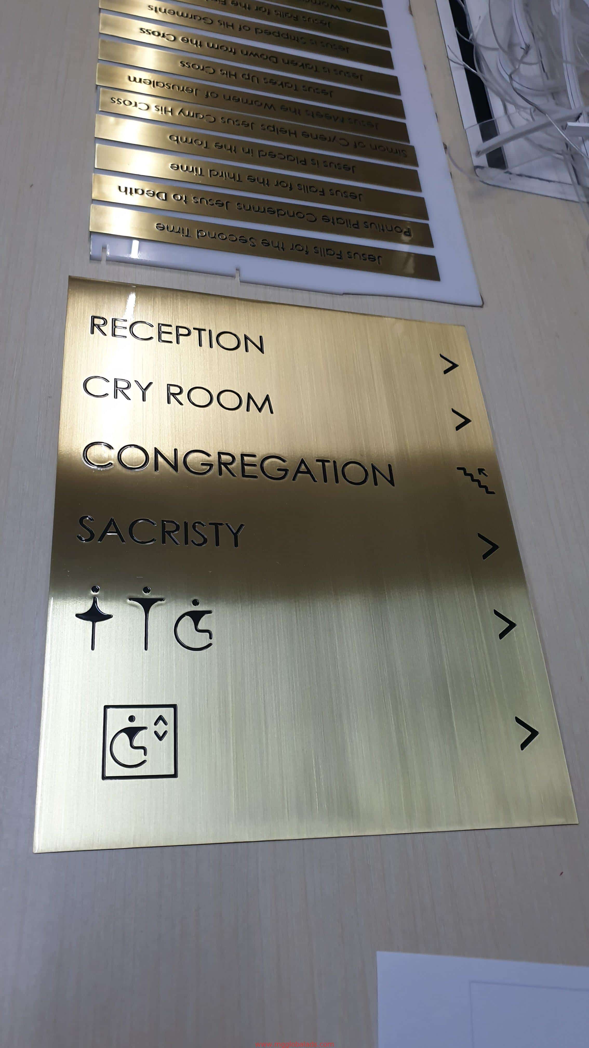 Wayfinding building brass signage in Makati: gold metallic sign with black text, arrows, and icons by M&G Global Ads.