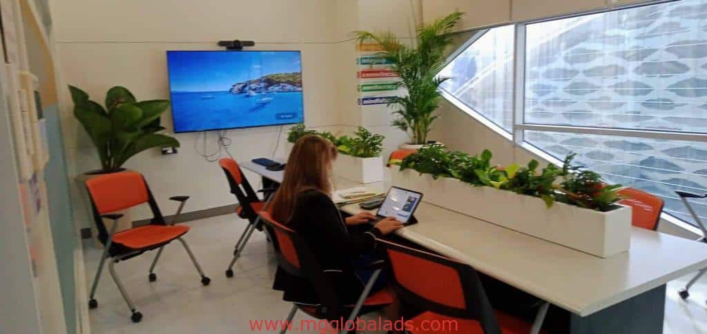 Office indoor signage for client in Makati, modern workspace with laptop, orange chairs, plants, by M&G Global Ads.