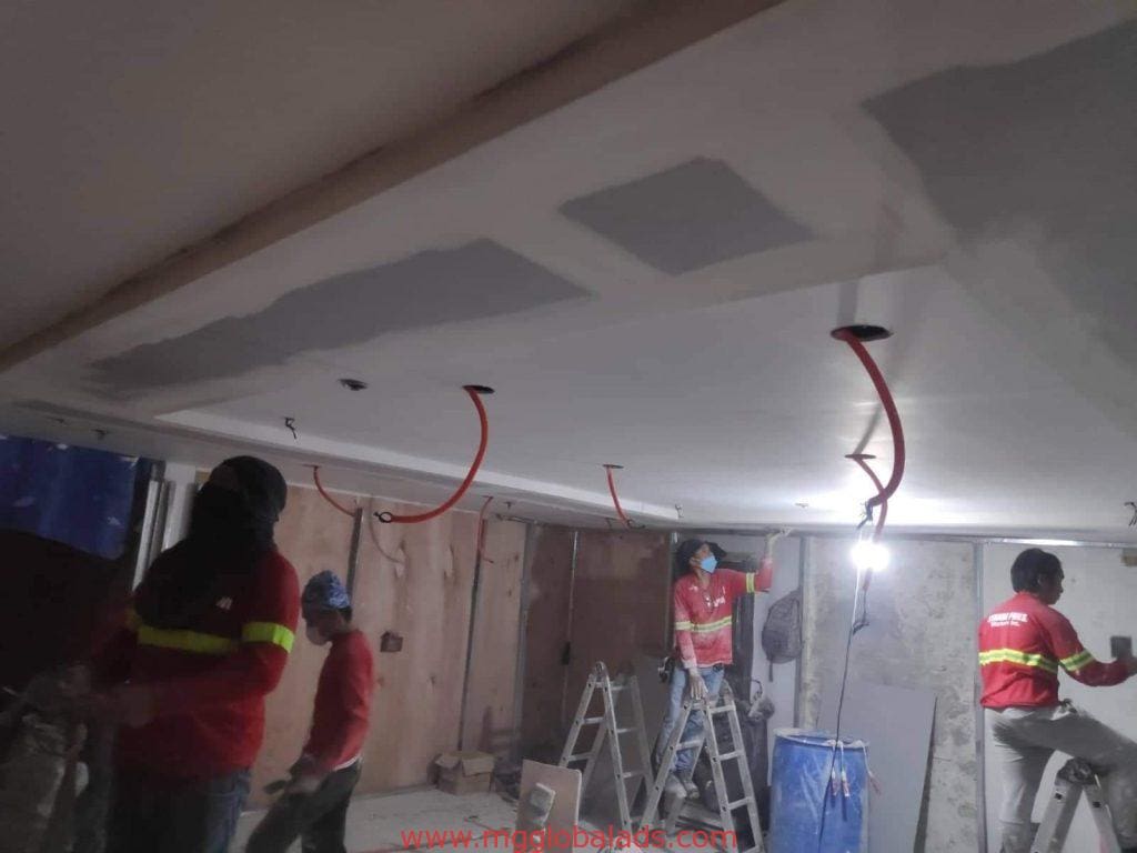 LED signage installation by four construction workers in Makati, indoor site with ladders and wiring, by M&G Global Ads.