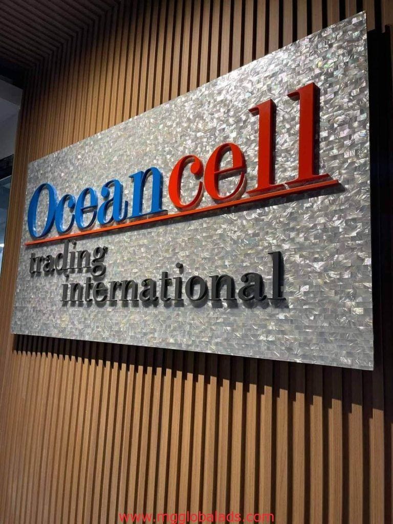 Metallic business signage for Oceancell, trading international, on wood panel in Ortigas by M&G Global Ads.