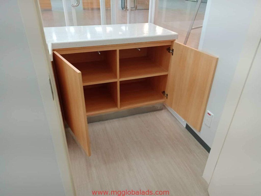 Wooden cabinet with empty compartments, white countertop, and sleek acrylic signage in Mandaluyong room by M&G Global Ads.