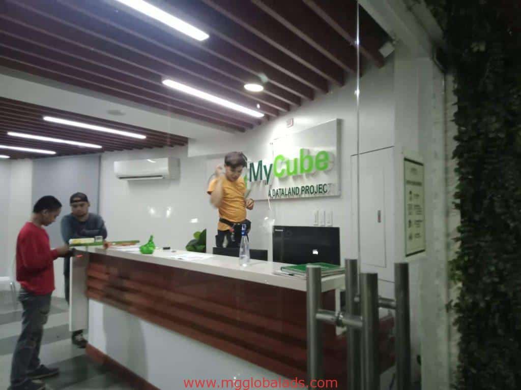 Acrylic building signage for MyCube OLANAD PROJECT at a modern office lobby in Makati, with people at the reception by M&G Global Ads.