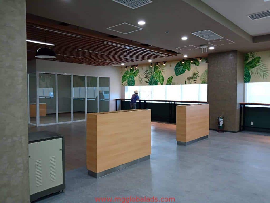 Modern office in Makati with indoor LED signage, glass partitions, greenery, and one person by railing by M&G Global Ads.