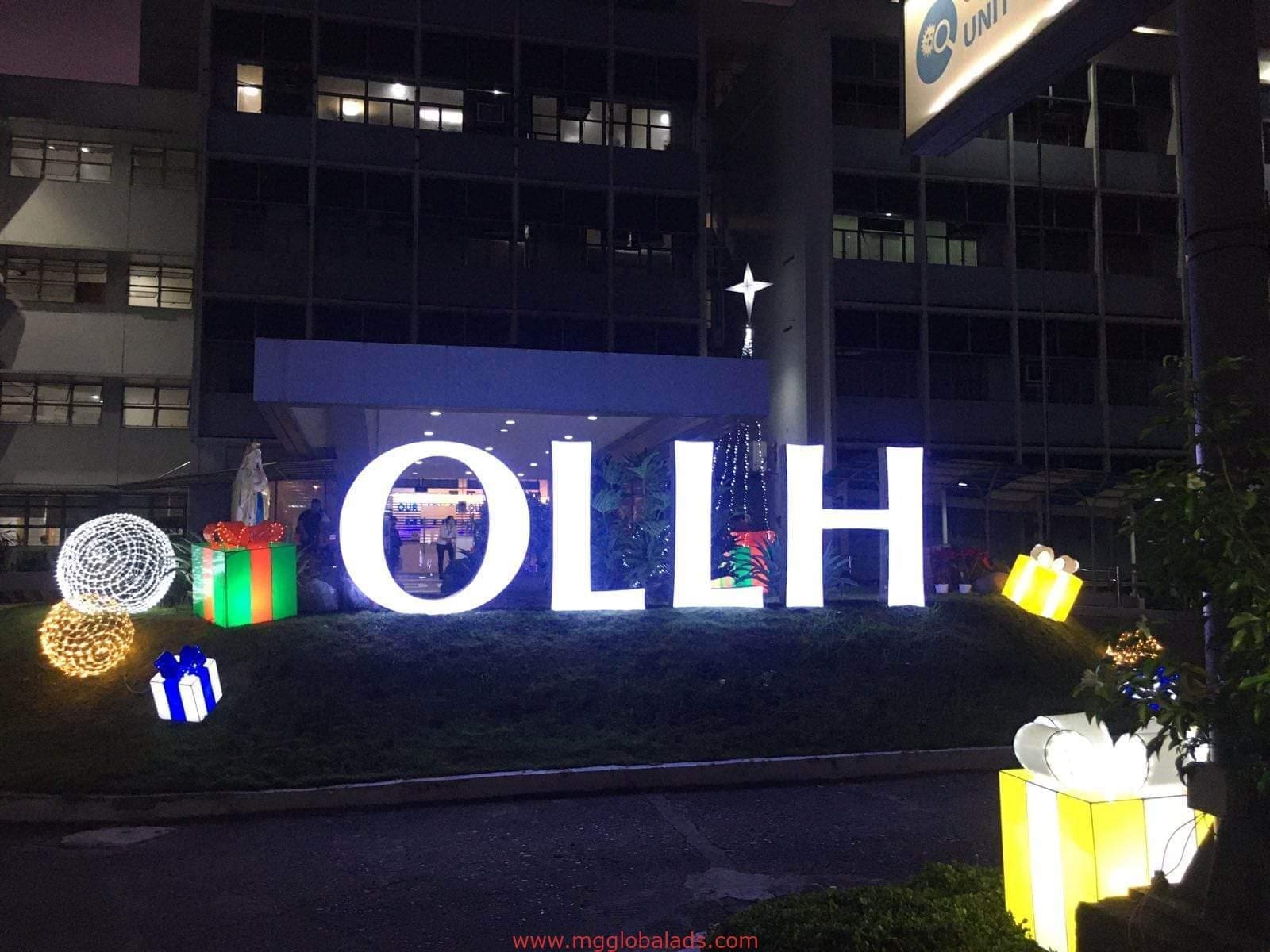 Large illuminated outdoor building signage for OLLH with Christmas decor at night in Quezon City by M&G Global Ads.