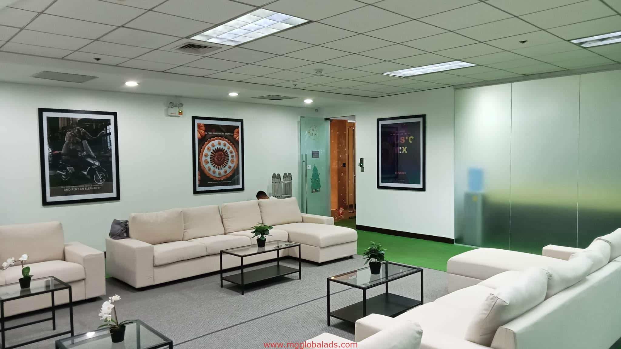 Modern office lounge with indoor acrylic signage in Makati, white sofas, glass tables, and plants. By M&G Global Ads.