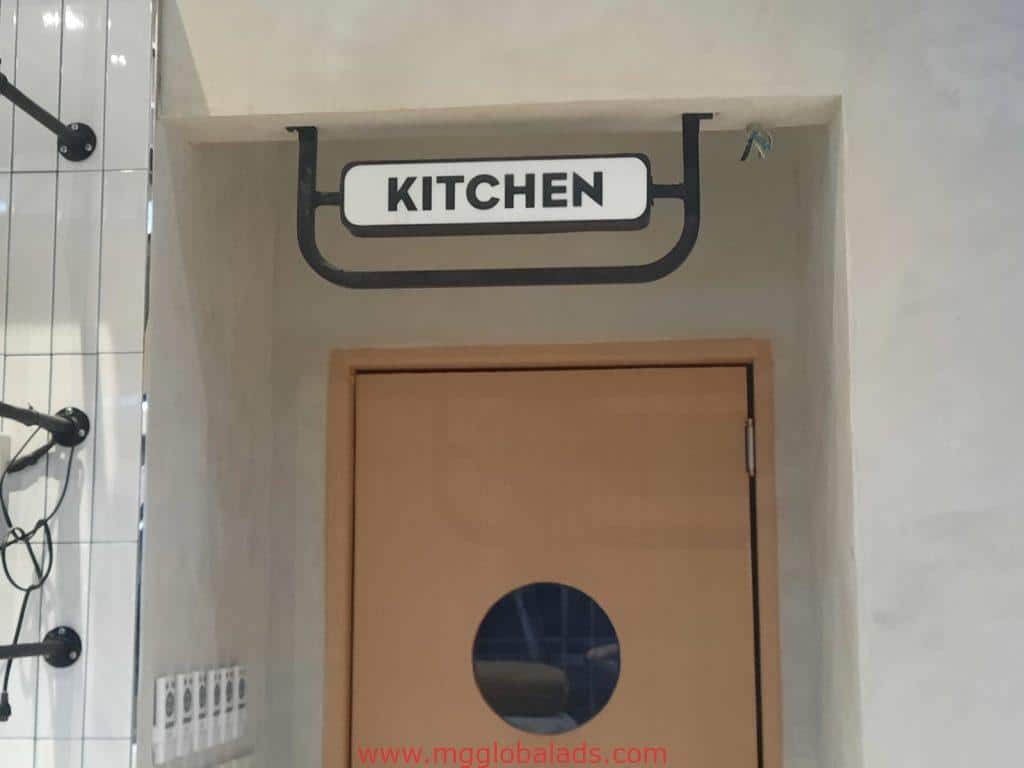 Acrylic kitchen door signage in Makati above a light brown door with a round window, neutral wall, by M&G Global Ads.