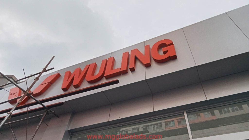 WULING LED signage with large red letters on a modern building in BGC, scaffolding on left. By M&G Global Ads.