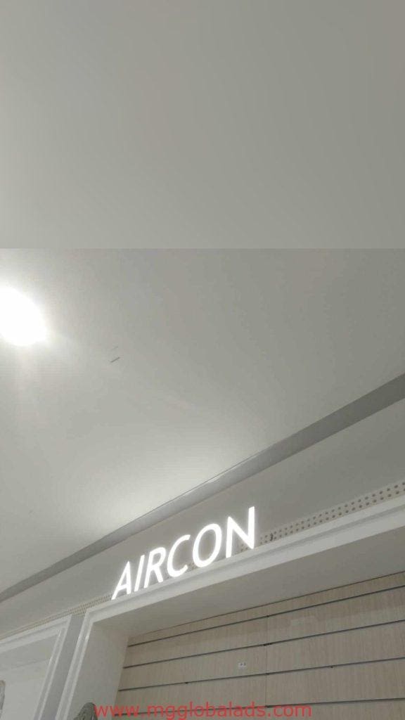 Indoor LED signage reading AIRCON above wood paneling in a Makati interior, ceiling lights visible; by M&G Global Ads.