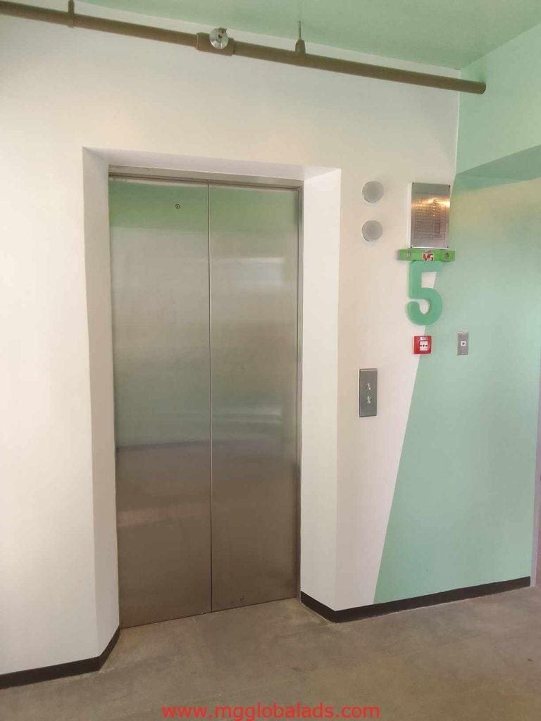 Acrylic elevator floor signage and emergency fire alarm in Makati modern building with closed stainless doors by M&G Global Ads.