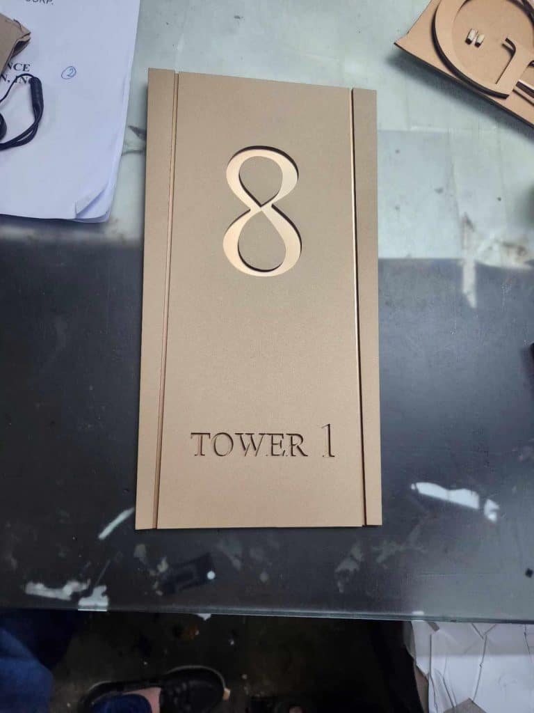 Acrylic number signage plaque for building, gold color, TOWER 1, seen in Makati office setting by M&G Global Ads.