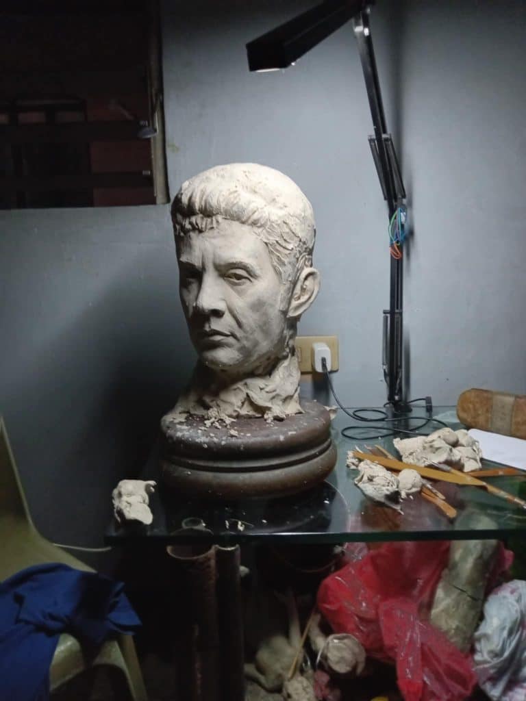Indoor signage elements with clay bust and sculpting tools on glass table in Makati, artistic studio lighting by M&G Global Ads.