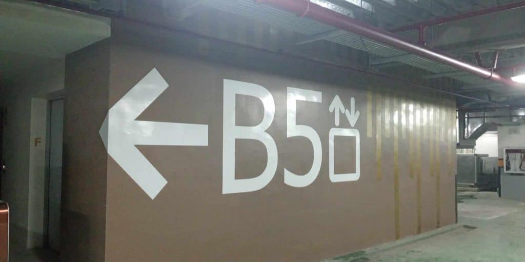 Metallic directional elevator signage B5 with arrow in Makati parking garage basement, interior wall display by M&G Global Ads.