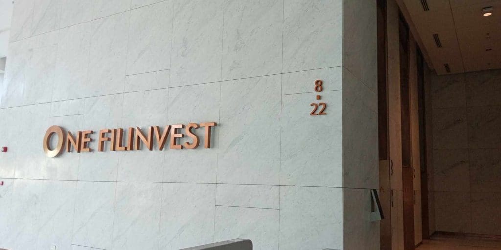 Metallic office signage for ONE FILINVEST with copper letters in Makati, marble wall background. By M&G Global Ads.