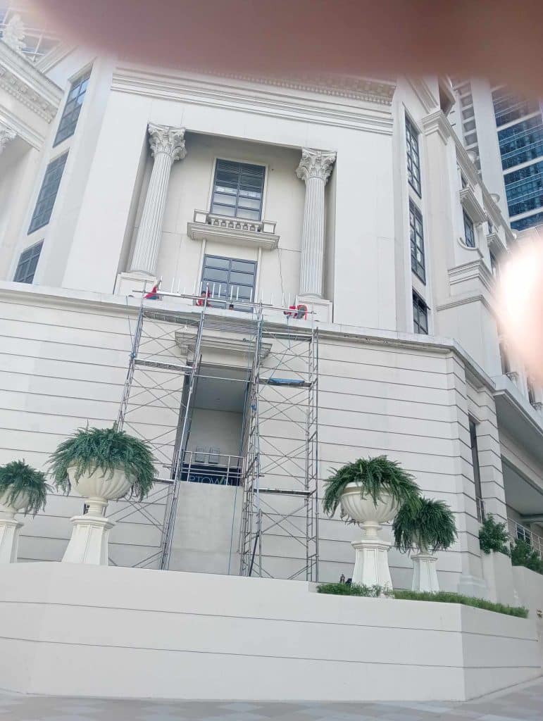 Outdoor building signage installation on a classical white building in Makati with workers on scaffolding by M&G Global Ads.
