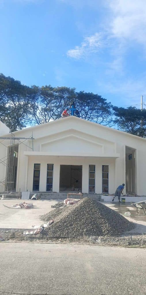 Outdoor billboard signage installation at a white building site in Quezon City under construction, by M&G Global Ads.