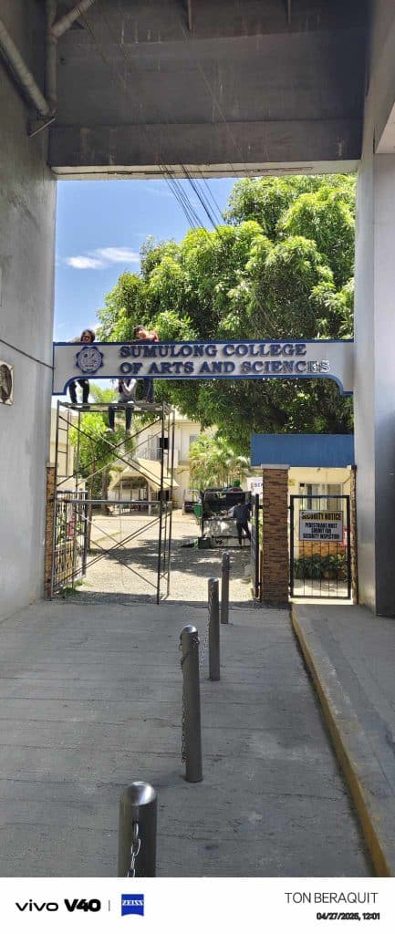 Sumulong College entrance metallic signage in Pasig, campus buildings and trees visible by M&G Global Ads.