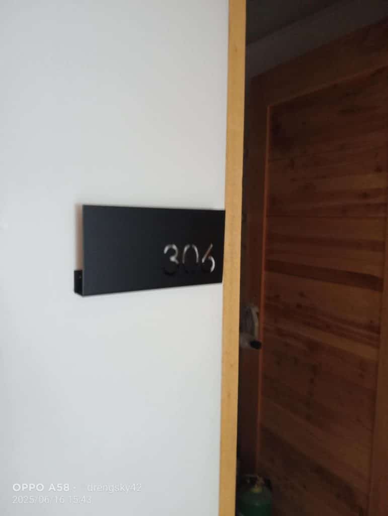 Room number signage 306, black metallic on white wall near wooden door in Makati apartment hallway by M&G Global Ads.