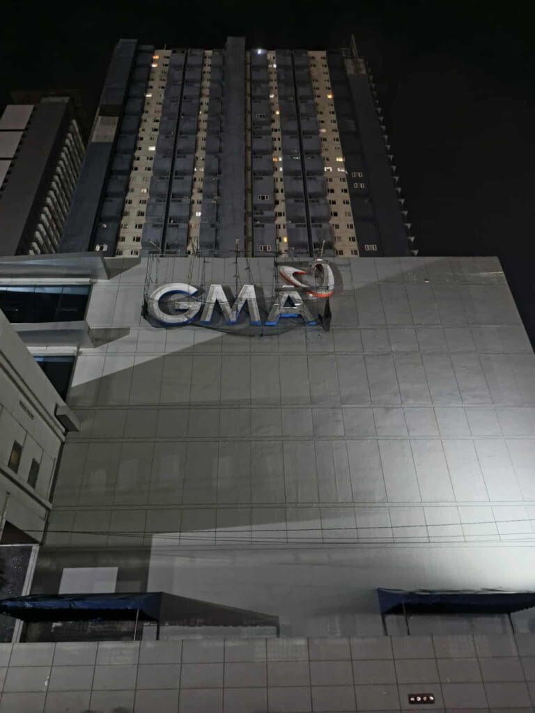 GMA illuminated acrylic LED signage with red heart on tall building facade at night, Metro Manila sign maker Philippines by M&G Global Ads.
