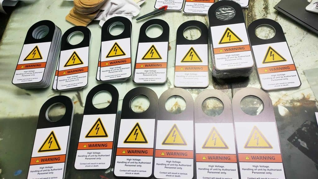 High voltage door hangers signage with safety messages for client in Pasig, spread on a table by M&G Global Ads.
