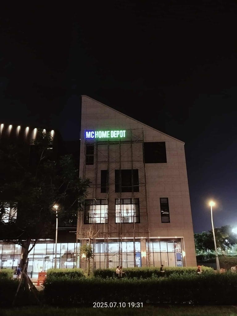 MC Home Depot LED signage on modern building exterior at night in Quezon City, trees and streetlights, by M&G Global Ads.