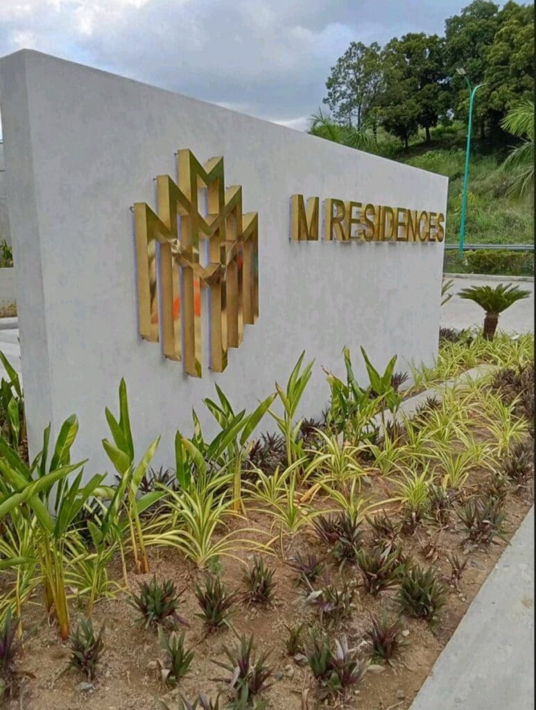Modern outdoor signage for M RESIDENCES with gold geometric logo in Makati landscaping by M&G Global Ads.