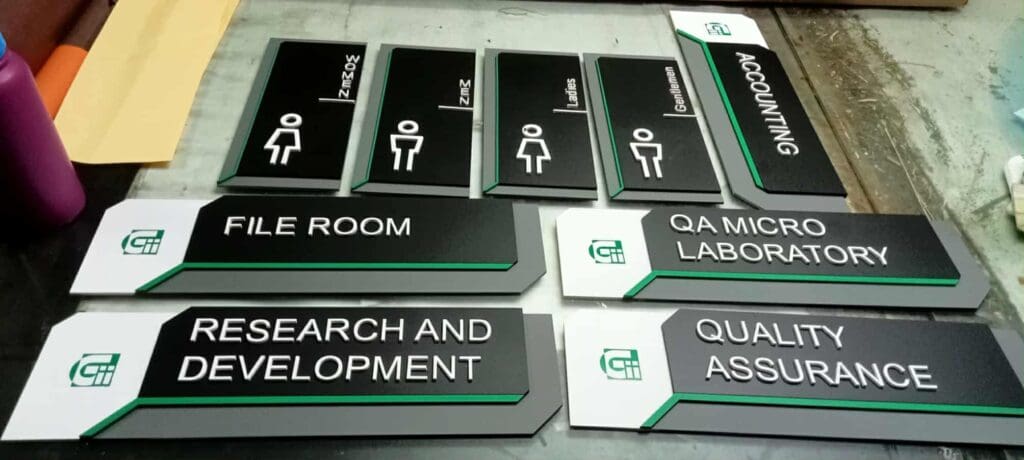 Office and restroom signage for corporate use, shown on table in Makati, by M&G Global Ads.