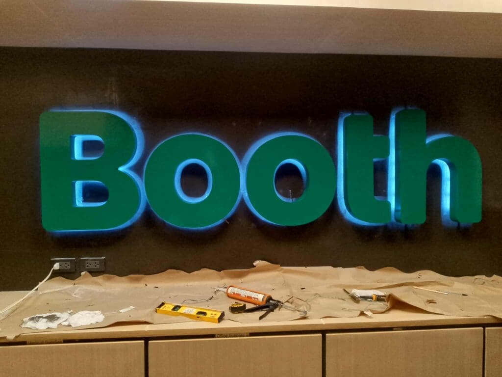 LED acrylic building signage with Booth in green, illuminated on dark wall, Metro Manila. Sign maker Philippines by M&G Global Ads.