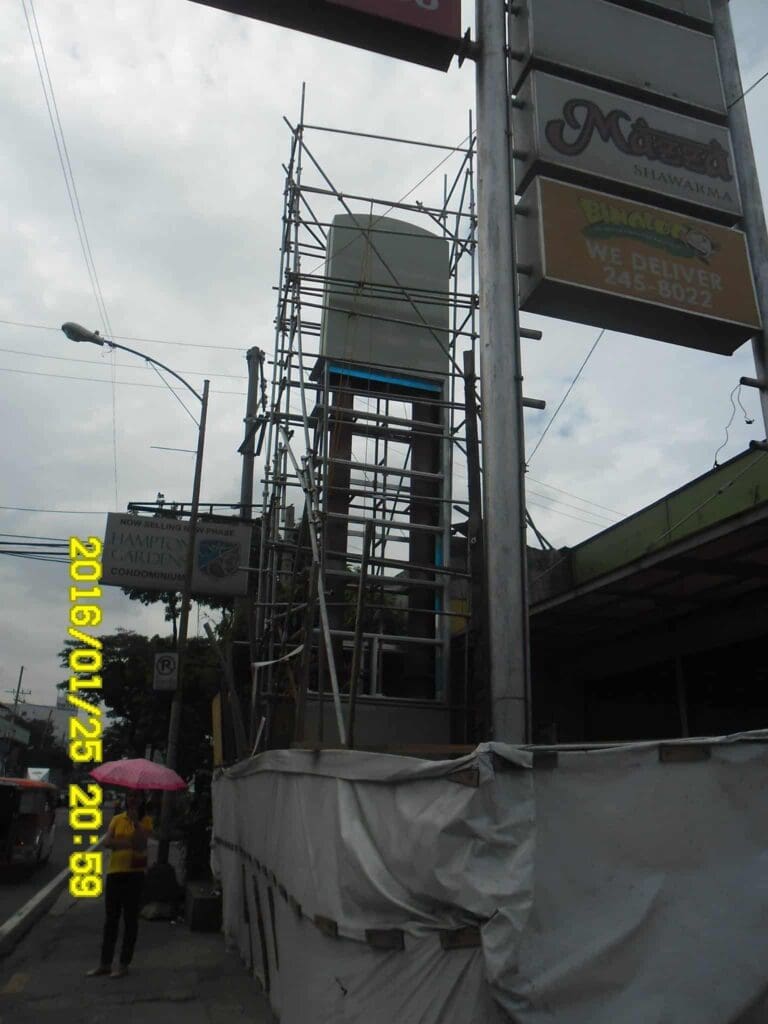 Outdoor building signage under construction with scaffolding, Metro Manila sidewalk scene, sign maker Philippines by M&G Global Ads.