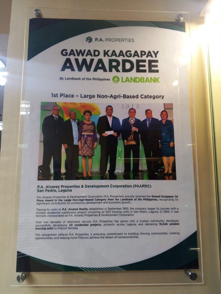 Acrylic indoor signage poster for P.A. Properties, announcing their 1st Place Large Non-Agri-Business Gawad Kaagapay Award by Landbank, featuring a group photo of six people onstage holding a trophy; sign maker Philippines by M&G Global Ads. Location: Philippines.