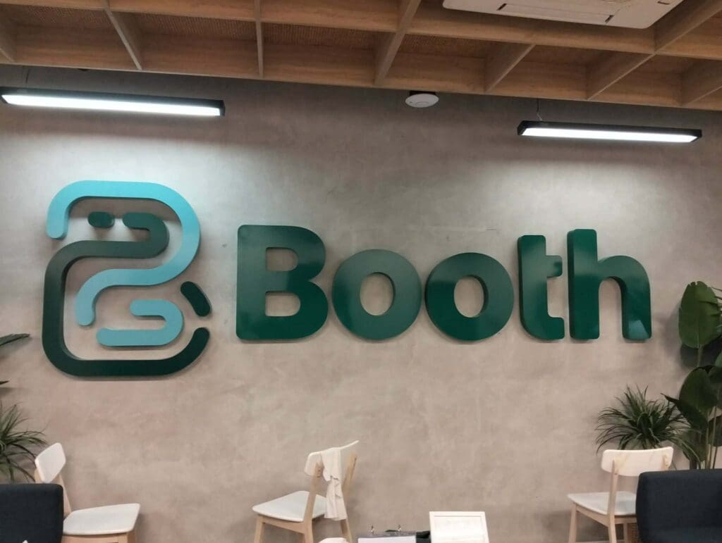 Acrylic indoor Booth signage with stylized B logo on grey wall, Metro Manila, by sign maker Philippines M&G Global Ads.
