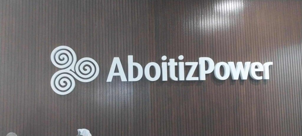 Acrylic indoor signage for AboitizPower with white logo on dark wood wall, Metro Manila. Sign maker Philippines by M&G Global Ads.