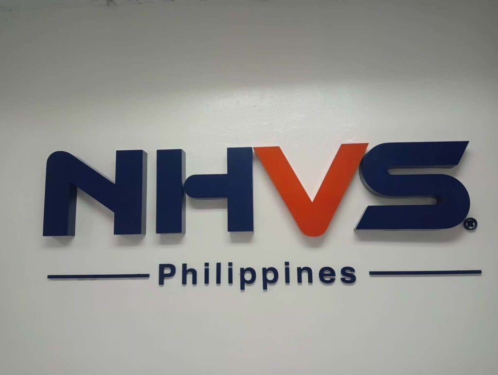 Acrylic indoor signage for NHVS, white wall, blue and orange letters, Philippines. Sign maker Philippines by M&G Global Ads.