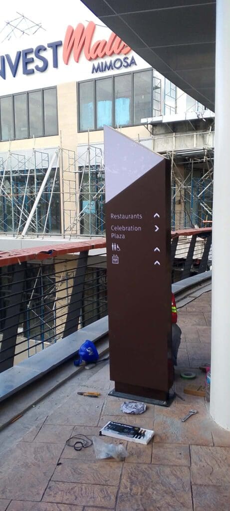 Brown acrylic wayfinding directional sign at mall under construction, Metro Manila, by sign maker Philippines M&G Global Ads.