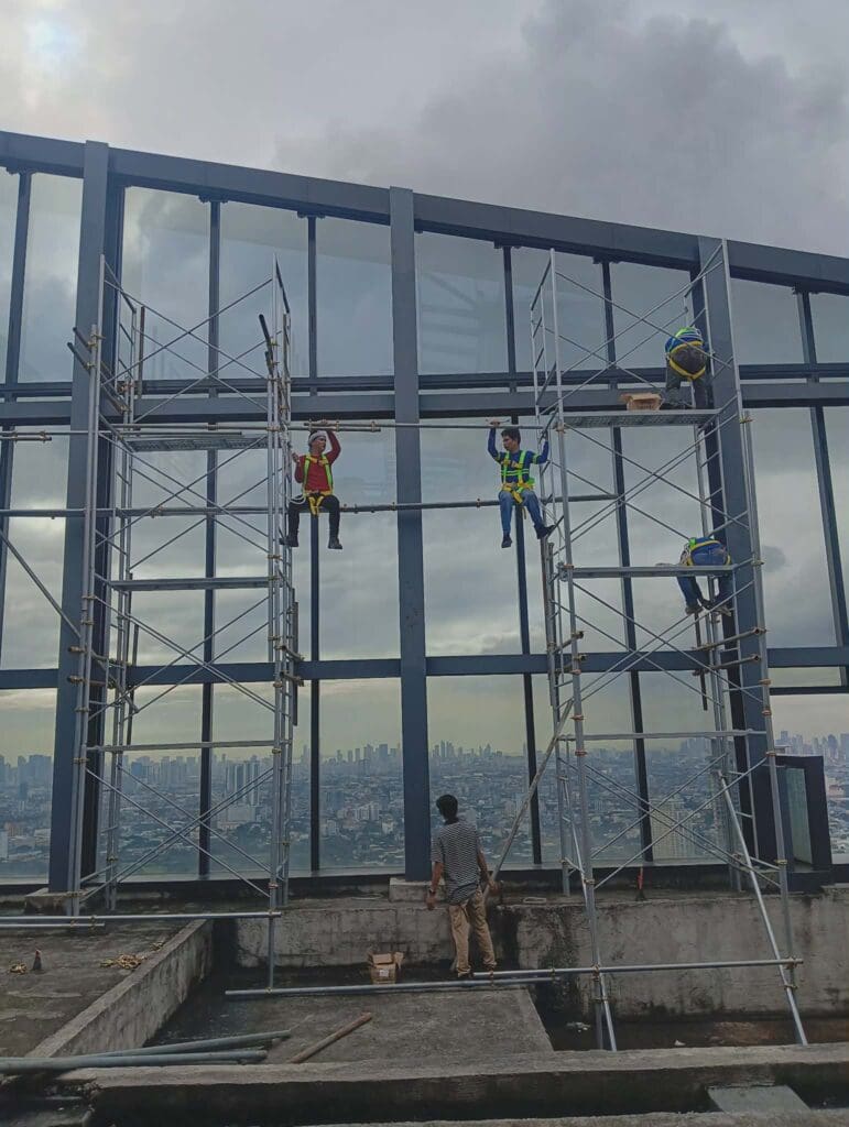 Building glass panel installation by sign maker Philippines, Metro Manila. Safety signage work on tall building by M&G Global Ads.